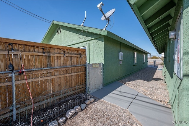 view of side of property with fence and stucco siding