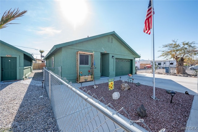 view of front facade with a garage, fence, driveway, and stucco siding