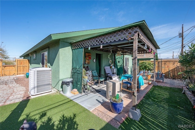 back of house featuring central AC, fence, a yard, stucco siding, and a patio area