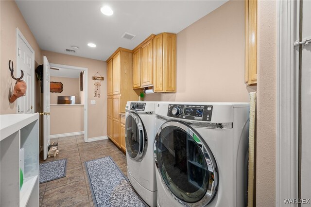 clothes washing area featuring independent washer and dryer, cabinet space, visible vents, and baseboards