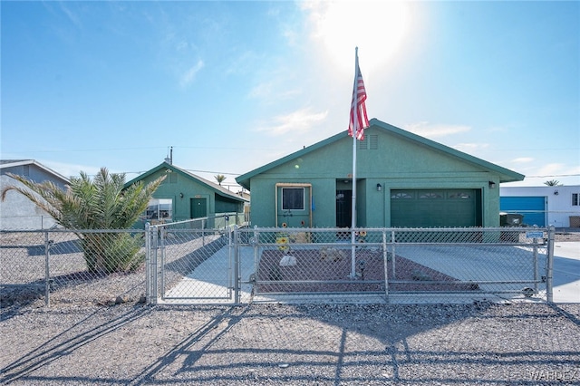 view of front facade featuring a fenced front yard, an attached garage, driveway, a gate, and stucco siding