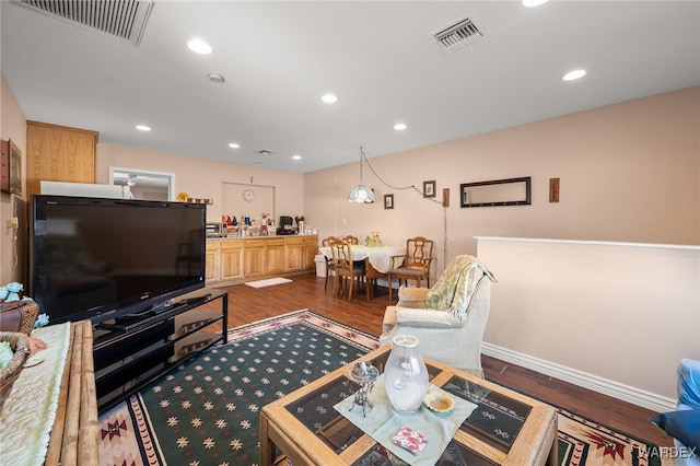 living area with dark wood-style flooring, visible vents, and recessed lighting