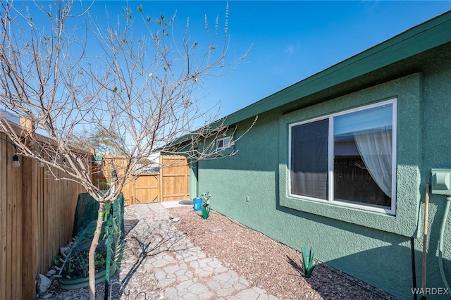 view of side of home with a fenced backyard and stucco siding