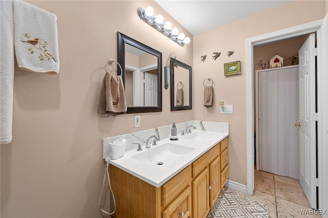 full bathroom featuring double vanity, tile patterned flooring, baseboards, and a sink