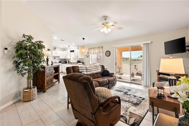 living area with light tile patterned floors, baseboards, ceiling fan, and vaulted ceiling