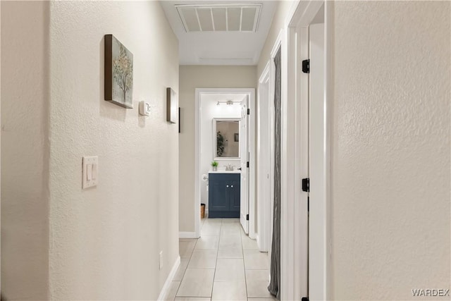 hallway featuring light tile patterned flooring, visible vents, and baseboards