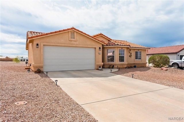 mediterranean / spanish-style house featuring a tile roof, concrete driveway, an attached garage, and stucco siding