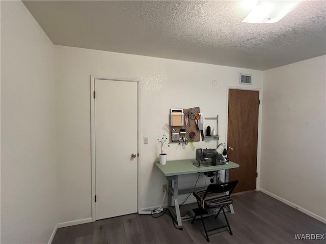 office featuring visible vents, a textured ceiling, baseboards, and wood finished floors