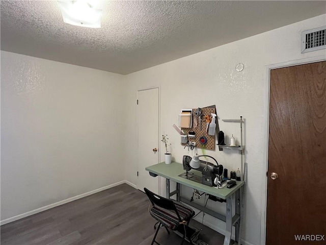 office space with a textured ceiling, wood finished floors, visible vents, and baseboards