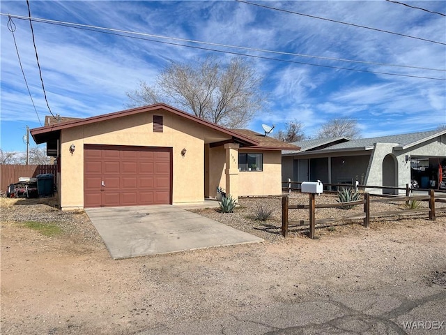 ranch-style home featuring a garage, fence, concrete driveway, and stucco siding