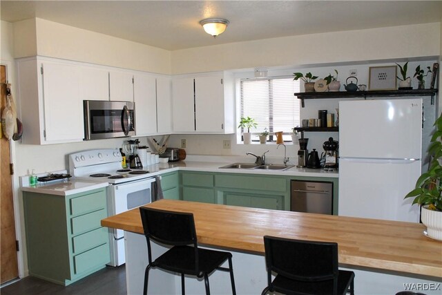 kitchen with butcher block counters, appliances with stainless steel finishes, white cabinets, and a sink