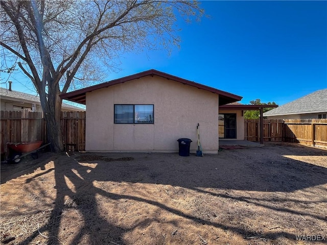 rear view of house with a patio area, a fenced backyard, and stucco siding