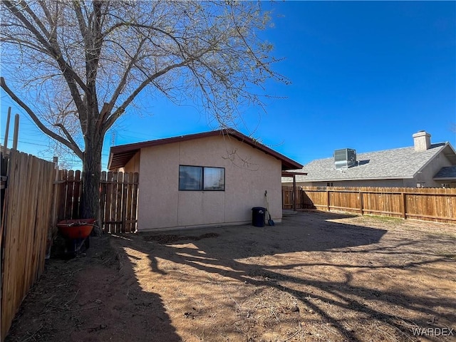 rear view of property with central air condition unit, a fenced backyard, and stucco siding