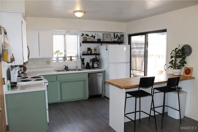 kitchen with dark wood-style floors, green cabinets, a sink, dishwasher, and a kitchen breakfast bar