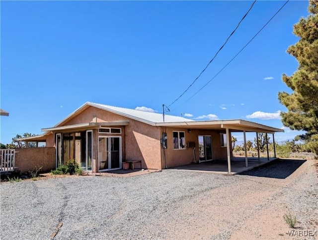 back of house with a carport, stucco siding, and driveway