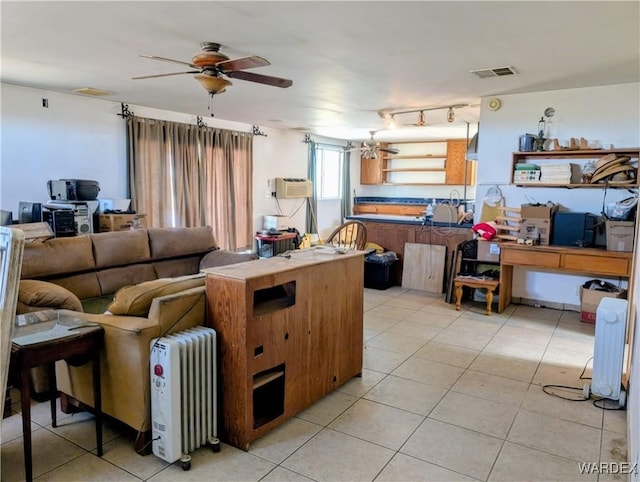 living area with radiator heating unit, light tile patterned floors, ceiling fan, and visible vents