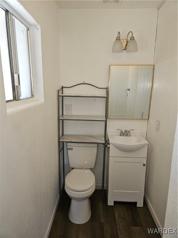 bathroom featuring toilet, baseboards, wood finished floors, and vanity