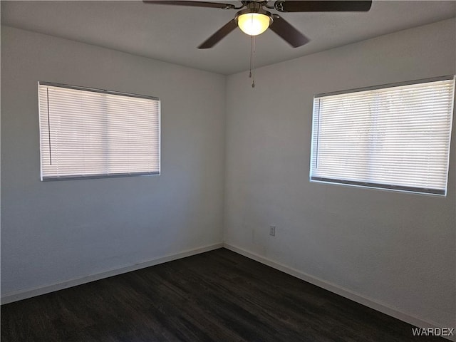 unfurnished room with dark wood-type flooring, a ceiling fan, and baseboards