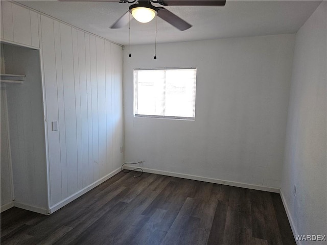 unfurnished bedroom with dark wood finished floors, a ceiling fan, and baseboards