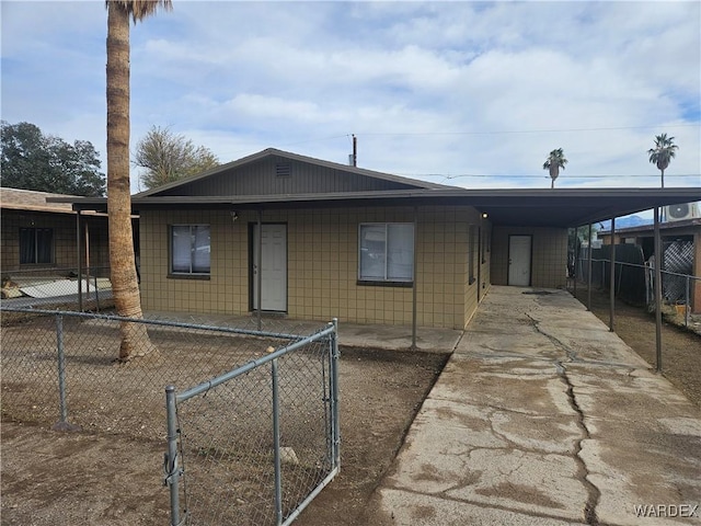 view of front facade with concrete driveway, a carport, and a fenced front yard