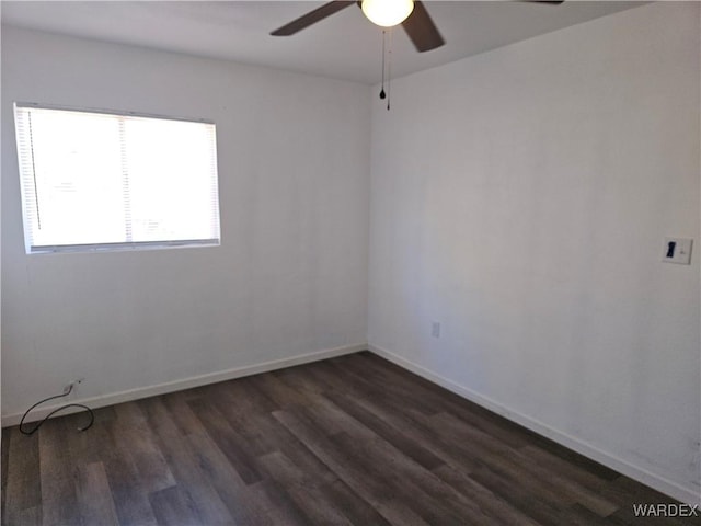 unfurnished room featuring baseboards, dark wood finished floors, and a ceiling fan