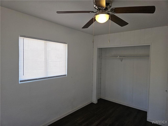 unfurnished bedroom with ceiling fan, a closet, baseboards, and dark wood-style flooring