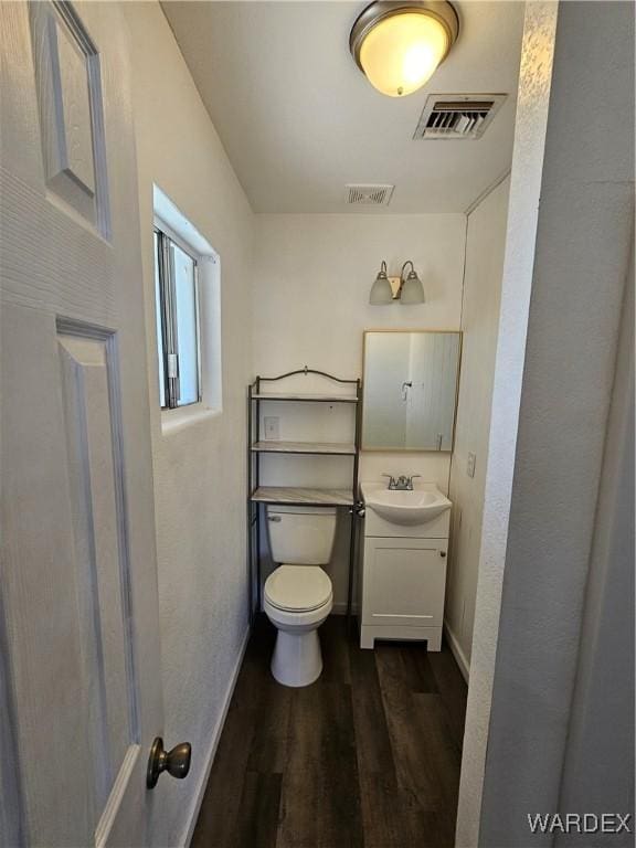 bathroom featuring toilet, vanity, wood finished floors, and visible vents