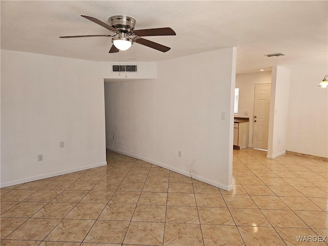 empty room with ceiling fan, visible vents, baseboards, and light tile patterned flooring