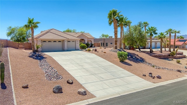 ranch-style house with fence, stucco siding, concrete driveway, a tile roof, and a garage
