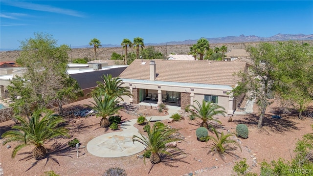 rear view of property with a tiled roof, covered porch, a mountain view, and stucco siding