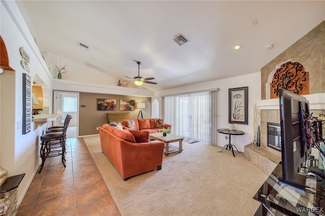 living area with a fireplace, lofted ceiling, visible vents, and ceiling fan
