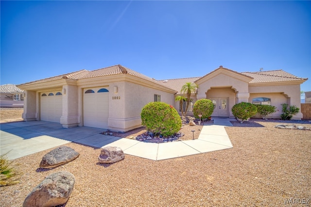 view of front of house featuring stucco siding, concrete driveway, a tiled roof, and an attached garage
