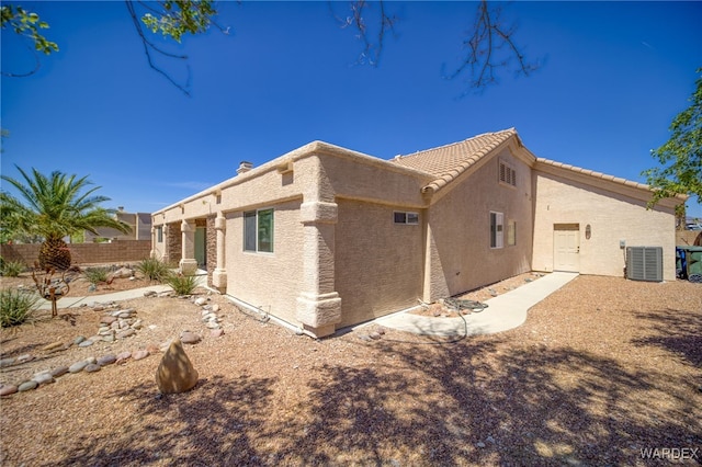 view of side of property with stucco siding, fence, and cooling unit