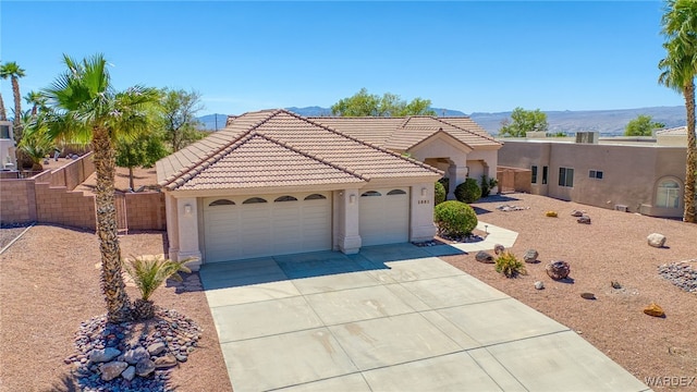 view of front of home with a tiled roof, concrete driveway, fence, a garage, and stucco siding