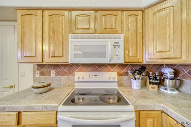 kitchen featuring decorative backsplash, tile counters, white appliances, and light brown cabinetry