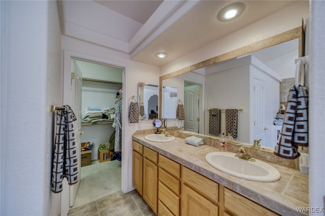 full bathroom featuring a spacious closet, a sink, and double vanity