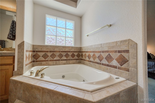 bathroom featuring a textured wall, vanity, and a tub with jets
