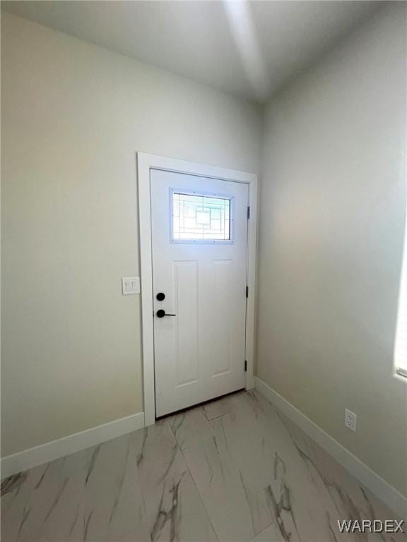 doorway to outside with marble finish floor and baseboards