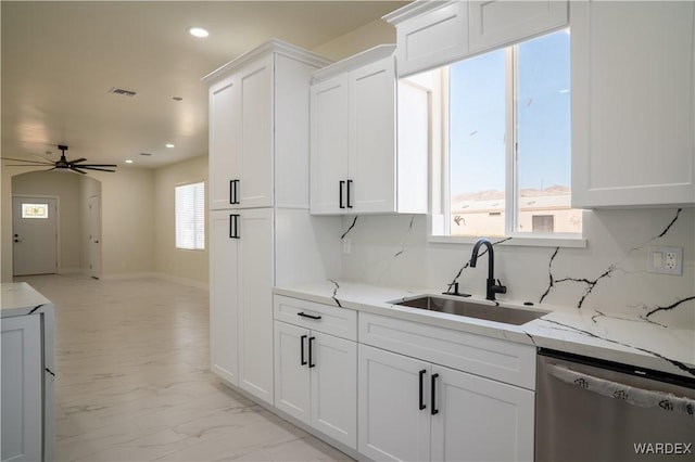 kitchen with open floor plan, stainless steel dishwasher, a sink, and white cabinets