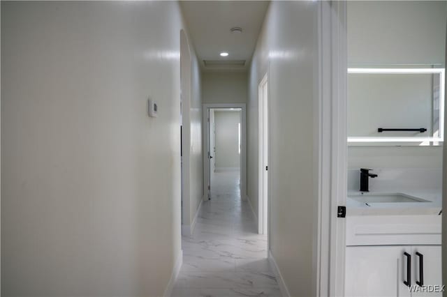 hall featuring marble finish floor, baseboards, and a sink