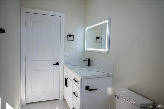 bathroom with marble finish floor, vanity, and toilet