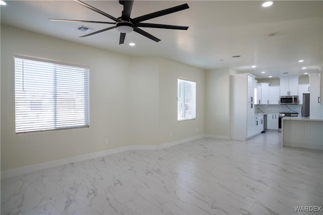 unfurnished living room featuring a wealth of natural light, recessed lighting, and marble finish floor