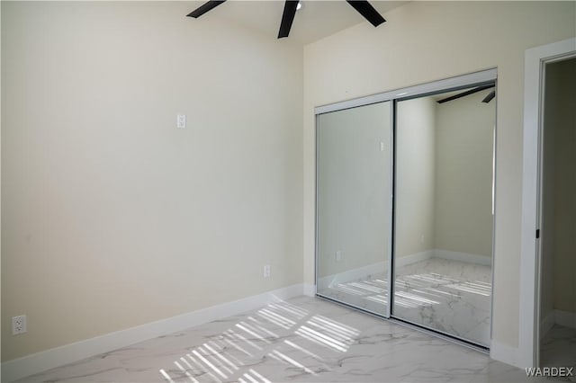 unfurnished bedroom with a closet, marble finish floor, and baseboards