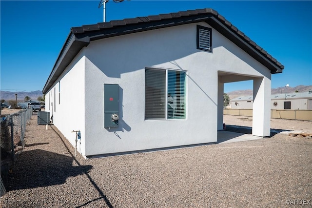 view of home's exterior with central air condition unit, a tile roof, fence, and stucco siding