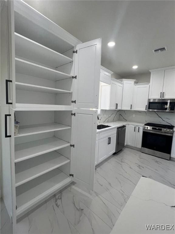 kitchen with marble finish floor, stainless steel appliances, visible vents, and white cabinetry