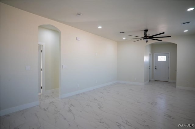 empty room featuring arched walkways, recessed lighting, visible vents, baseboards, and marble finish floor