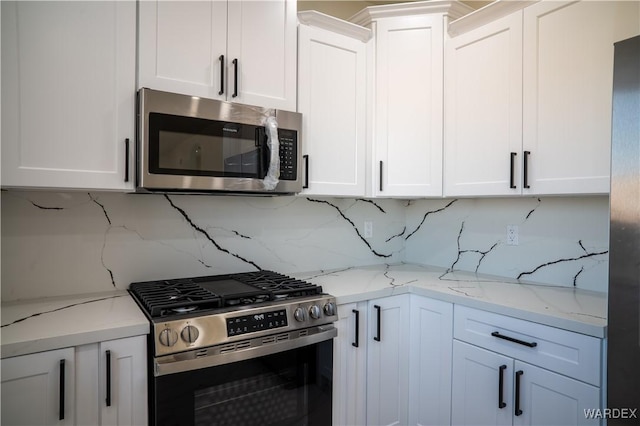 kitchen featuring light stone countertops, appliances with stainless steel finishes, white cabinets, and backsplash