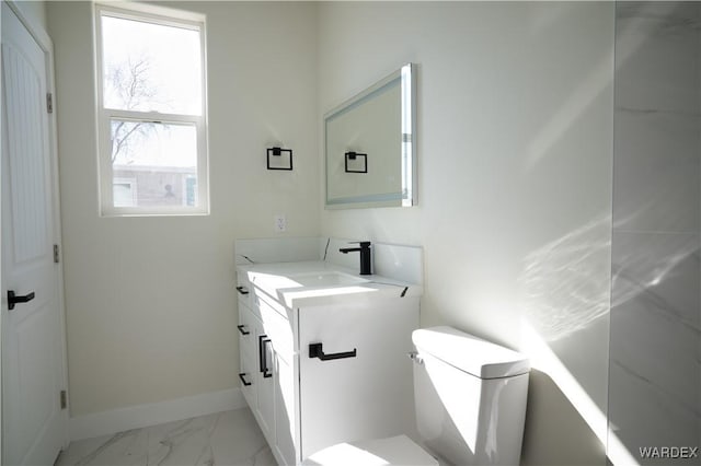 bathroom with toilet, marble finish floor, vanity, and baseboards