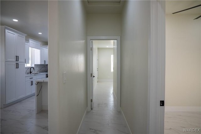 corridor featuring marble finish floor, recessed lighting, and baseboards