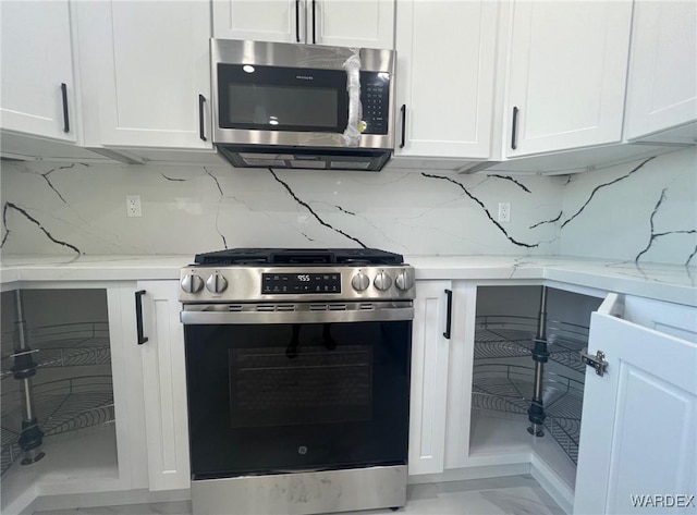 kitchen featuring appliances with stainless steel finishes, decorative backsplash, white cabinetry, and light stone countertops